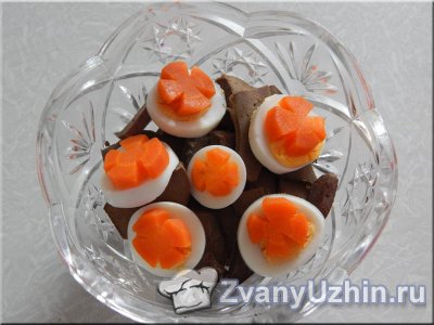 Сверху на печень выкладываем кружочки яиц и морковь